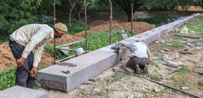Stone craftsmen installing hand chiselled granite stone on the plinth of the Tomb of Abdullah Qutb Shah