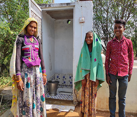 Vagtu Bai's daughter-in-law, nephew and niece pose in front of their toilet