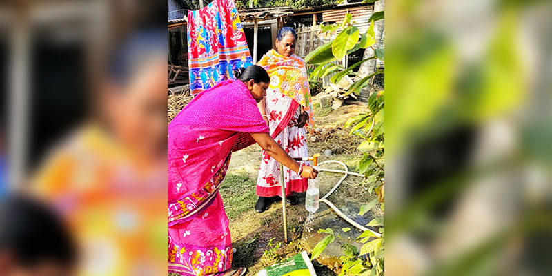 A committee member collecting a water sample from a beneficiary tap