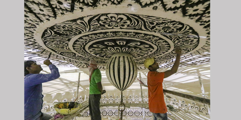 Craftsmen repair and paint the ceiling medallion at the Tomb of Abdullah Qutb shah