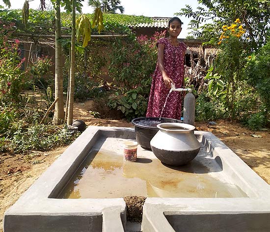 A beneficiary gets water at her doorstep A beneficiary gets water at her doorstep