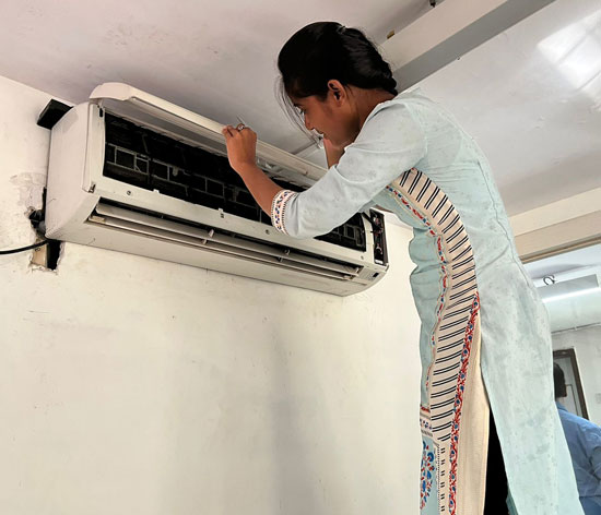 Mrunali inspecting an indoor AC unit