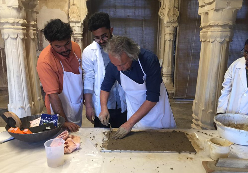 Course leader Anupam Sah demonstrating application of mud plaster replicating the plaster composition of Ajanta cave paintings