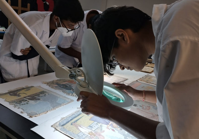 Participants inspecting the condition of an assortment of miniature paintings