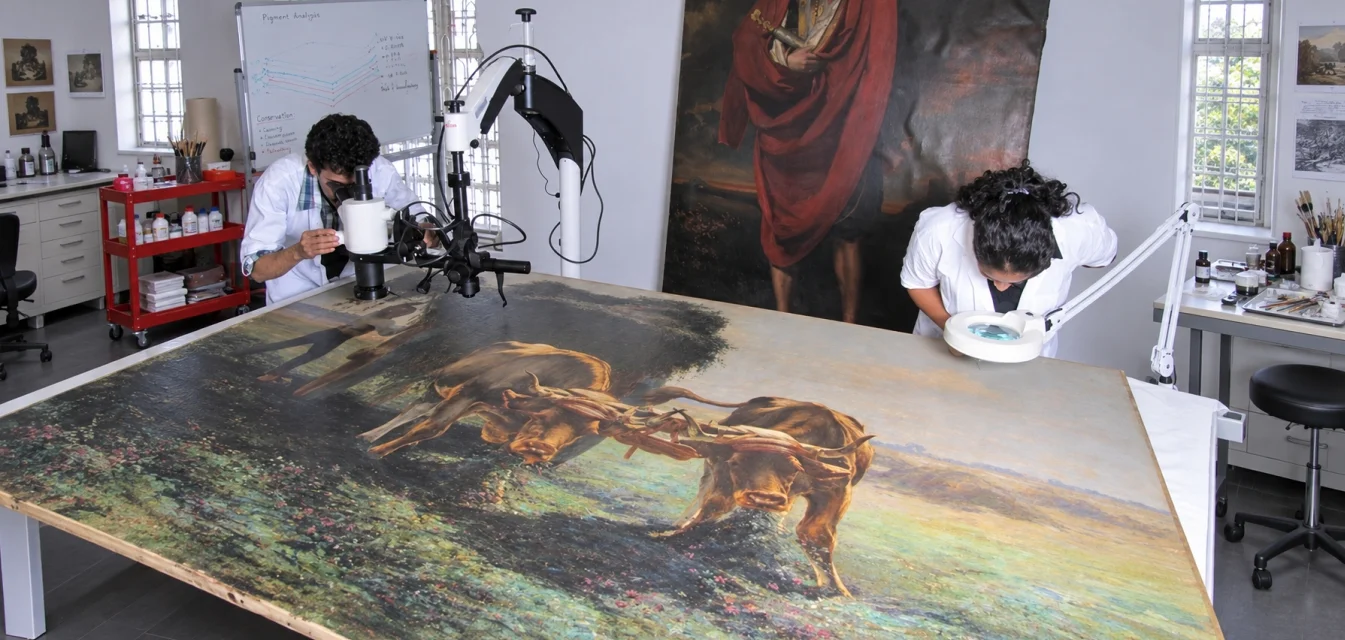 Conservators undertaking the conservation of an oil painting at the CSMVS conservation centre, during the ACRP project
