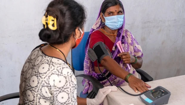 Health worker screening a woman during a community health visit