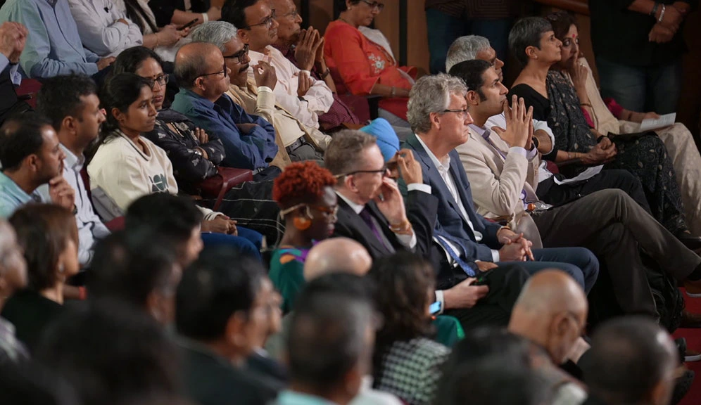 Nobel laureates and speakers sit among the audience, fully engaged in the ongoing session.