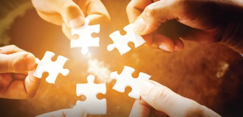 Hands joining puzzle pieces to represent institutional partnership